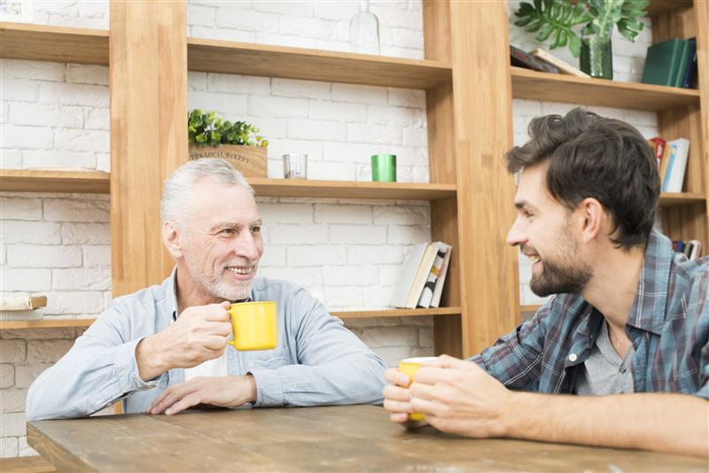 smiling-aged-man-happy-young-guy-with-cups-table